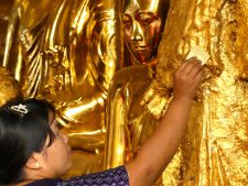 Dépôt rituel d'une feuille d'or sur un Bouddha de la pagode de Shwedagon à Yangon